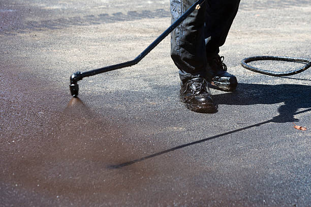 Worker applying seal coat to an asphalt surface